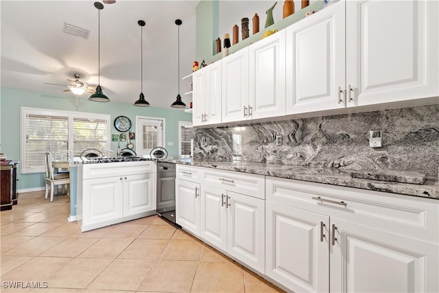 kitchen with light stone countertops, backsplash, light tile patterned floors, decorative light fixtures, and white cabinets