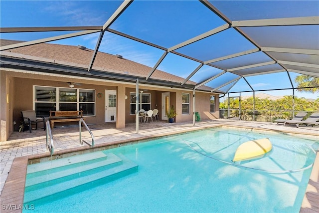 view of pool featuring glass enclosure, ceiling fan, and a patio