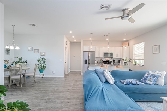 living room featuring ceiling fan with notable chandelier