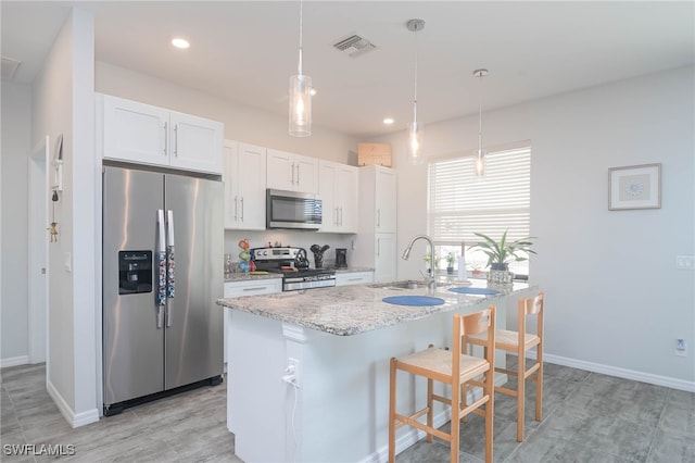 kitchen with white cabinetry, sink, hanging light fixtures, a center island with sink, and appliances with stainless steel finishes