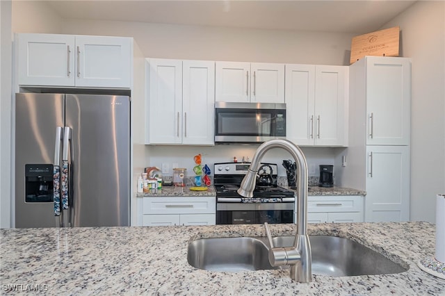 kitchen featuring white cabinets, sink, light stone counters, and stainless steel appliances