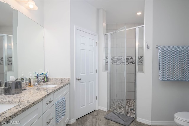 bathroom with tile patterned floors, vanity, toilet, and a shower with door