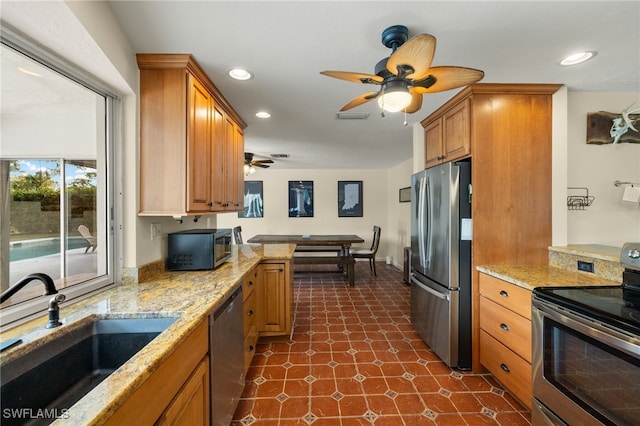 kitchen with appliances with stainless steel finishes, a sink, light stone counters, and recessed lighting