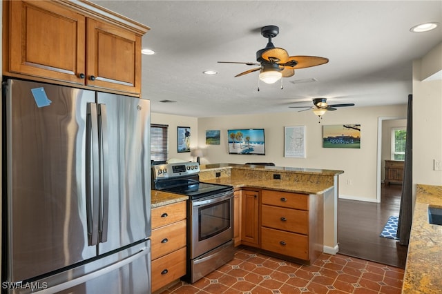 kitchen featuring brown cabinets, recessed lighting, appliances with stainless steel finishes, light stone countertops, and a peninsula