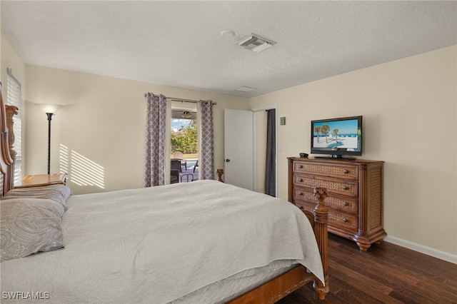 bedroom with dark wood-style flooring, visible vents, a textured ceiling, and baseboards