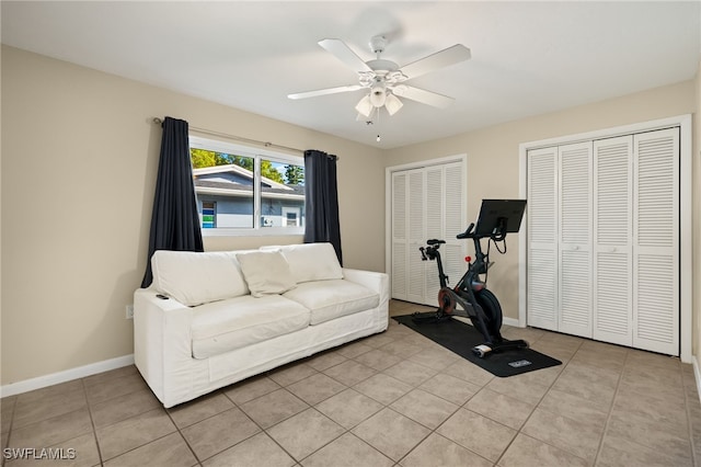 exercise area with light tile patterned flooring, ceiling fan, and baseboards