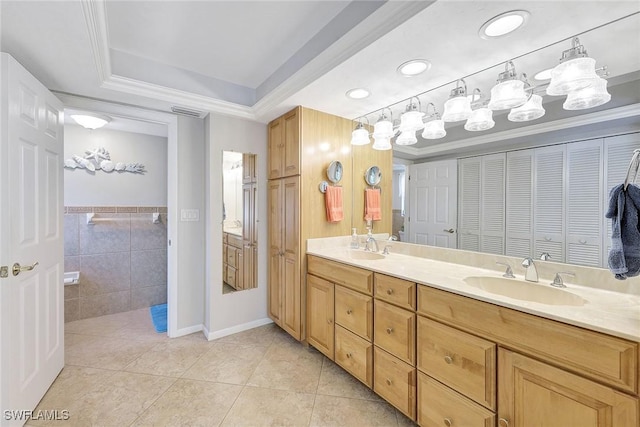 bathroom with tile patterned floors, ornamental molding, vanity, a raised ceiling, and tile walls