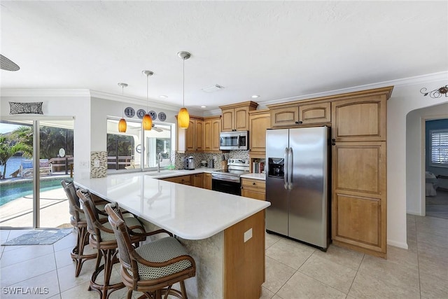 kitchen with stainless steel appliances, crown molding, pendant lighting, a kitchen bar, and light tile patterned flooring