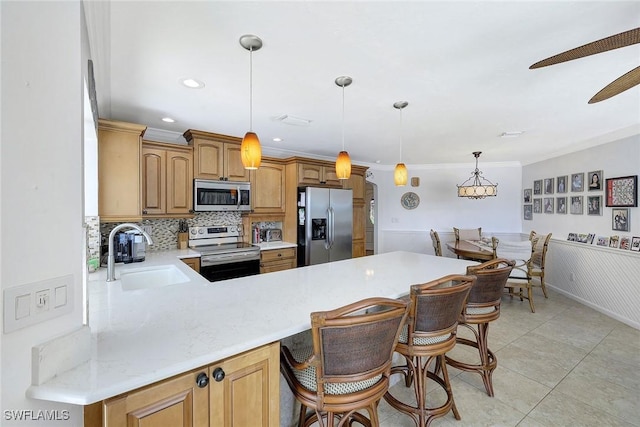 kitchen with sink, stainless steel appliances, a kitchen breakfast bar, kitchen peninsula, and decorative light fixtures