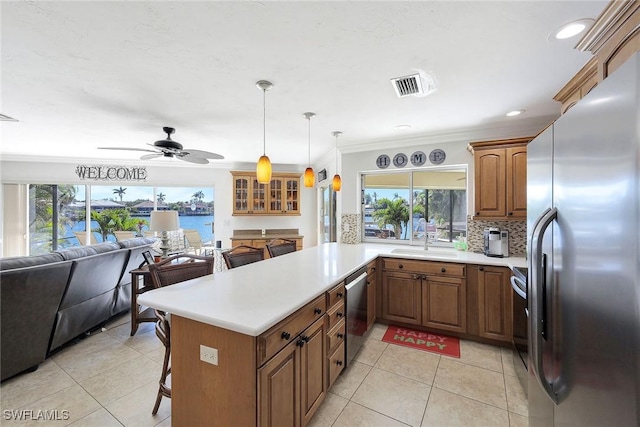 kitchen with kitchen peninsula, a breakfast bar, stainless steel appliances, a water view, and hanging light fixtures