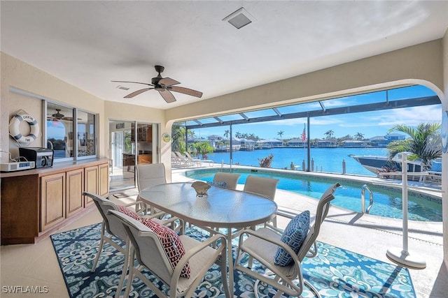 sunroom / solarium featuring ceiling fan and a water view