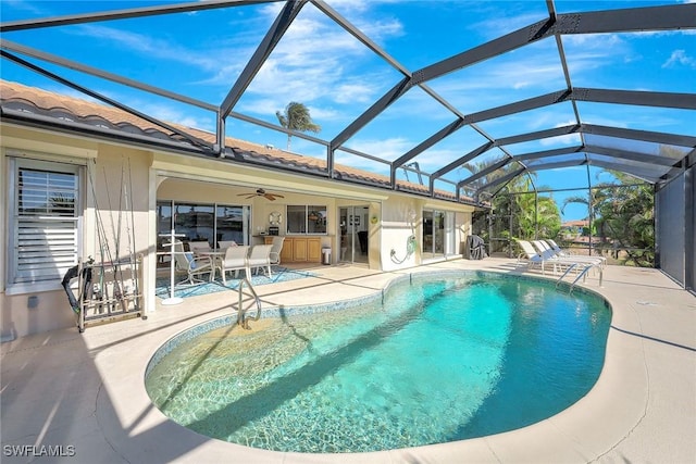 view of pool with glass enclosure, a patio area, and a bar