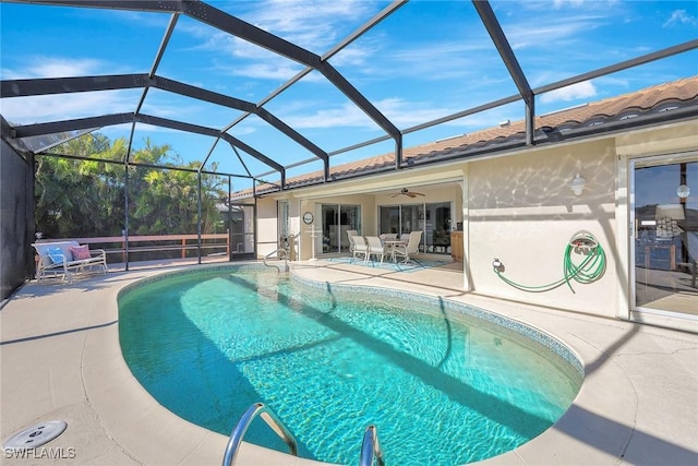 view of pool with a patio, glass enclosure, and ceiling fan