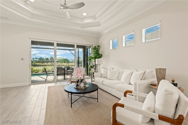 living room featuring wood-type flooring, a tray ceiling, ceiling fan, and ornamental molding