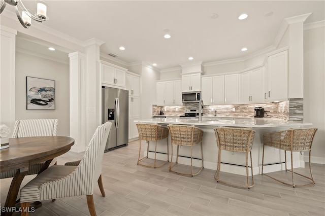 kitchen with white cabinets, a kitchen breakfast bar, light wood-type flooring, and appliances with stainless steel finishes