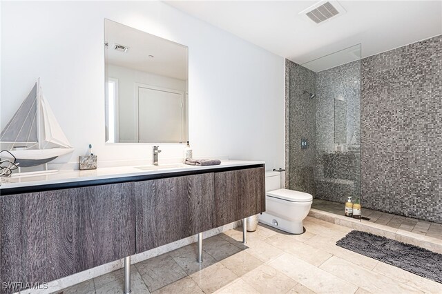 bathroom featuring vanity, toilet, and tiled shower