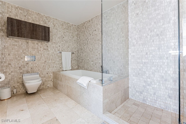 bathroom featuring tiled bath, tile patterned flooring, tile walls, and toilet