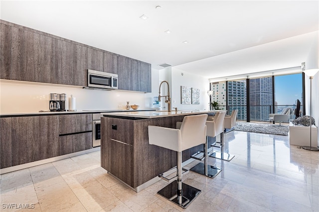 kitchen featuring sink, a kitchen bar, an island with sink, and stainless steel appliances