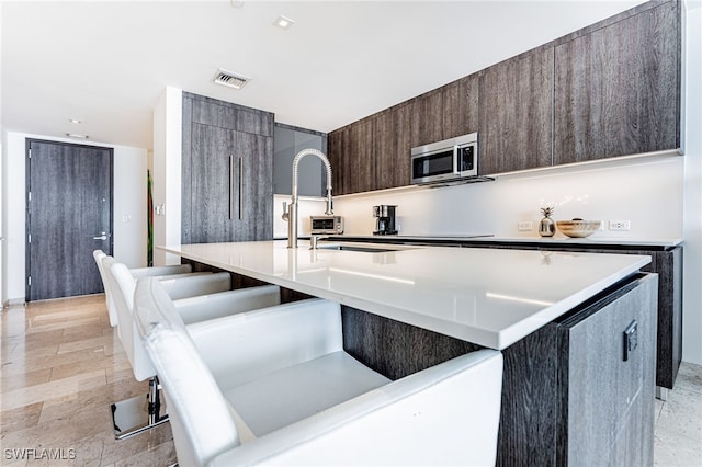 kitchen featuring dark brown cabinets and a center island with sink