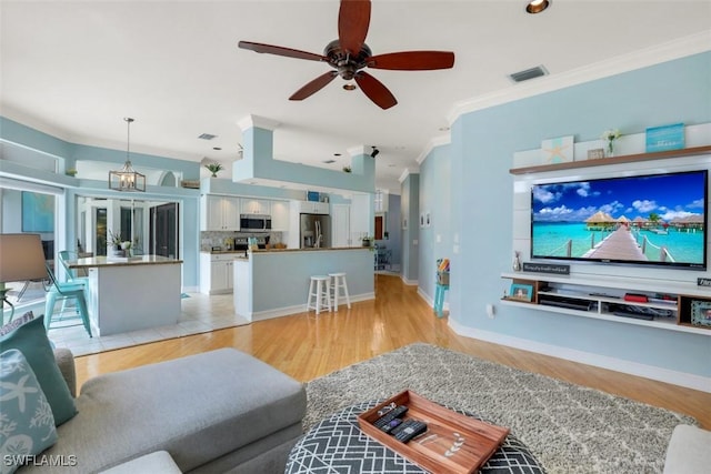 living room with light wood-type flooring, ceiling fan, and crown molding