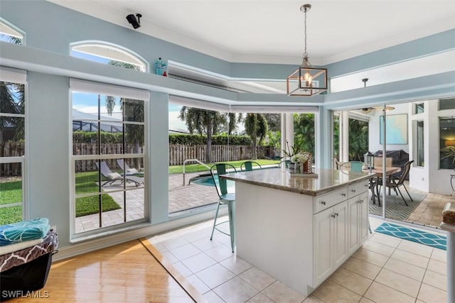 kitchen featuring a center island, a healthy amount of sunlight, light stone counters, and white cabinetry