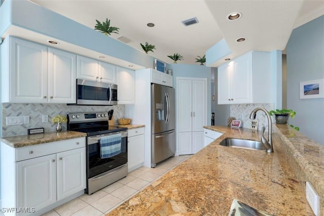 kitchen with decorative backsplash, appliances with stainless steel finishes, sink, light tile patterned floors, and white cabinetry