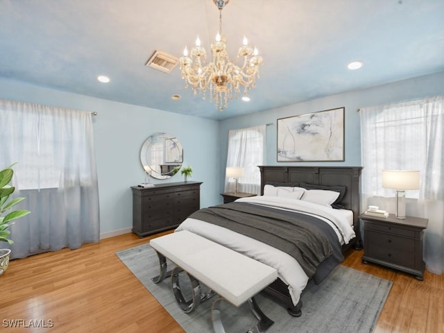 bedroom featuring a chandelier, light wood-type flooring, and multiple windows