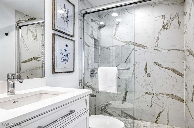 bathroom featuring a shower with door, vanity, and toilet