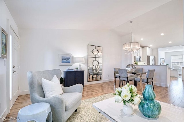 living room with light hardwood / wood-style floors, a notable chandelier, and lofted ceiling