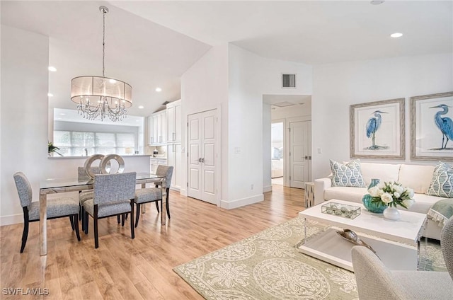 living room featuring lofted ceiling, light hardwood / wood-style flooring, and a chandelier