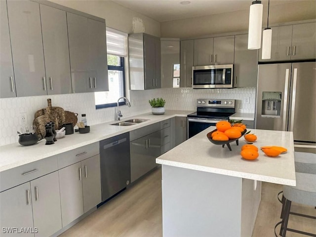 kitchen with appliances with stainless steel finishes, gray cabinetry, pendant lighting, and sink