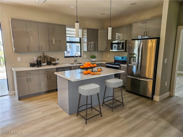 kitchen with a center island, a kitchen breakfast bar, hanging light fixtures, light wood-type flooring, and stainless steel appliances