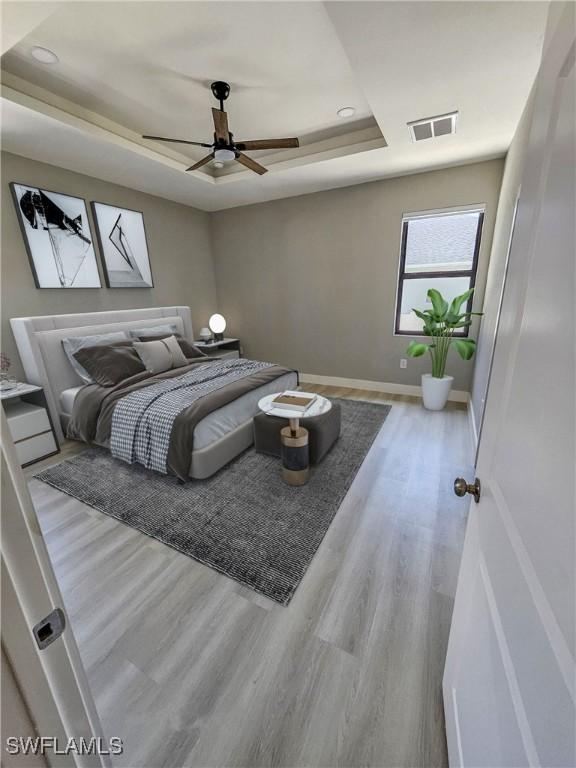 bedroom featuring light hardwood / wood-style floors, a raised ceiling, and ceiling fan