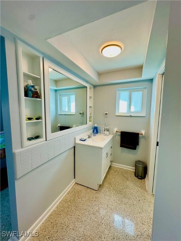 bathroom with a raised ceiling, plenty of natural light, and vanity