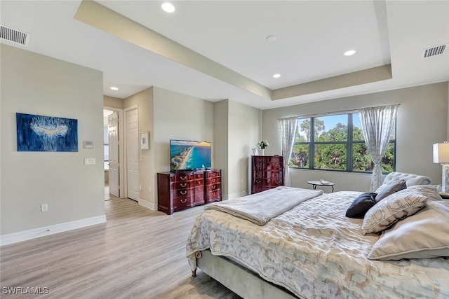 bedroom featuring a raised ceiling and light hardwood / wood-style floors