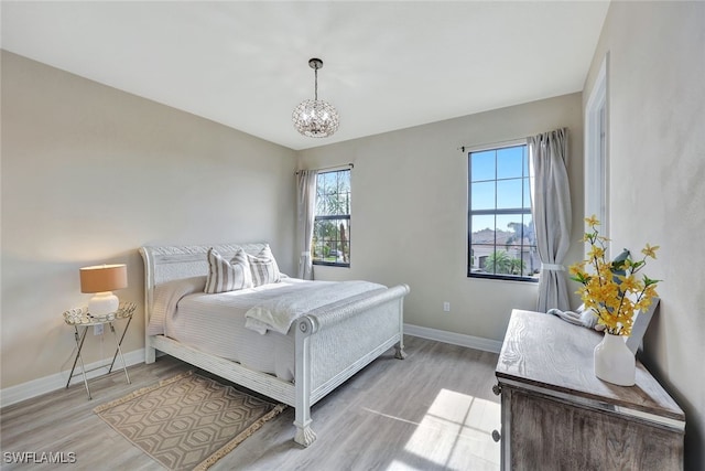 bedroom with a notable chandelier and light wood-type flooring