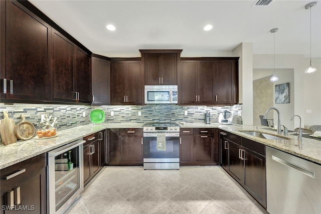 kitchen with appliances with stainless steel finishes, pendant lighting, sink, beverage cooler, and light stone countertops