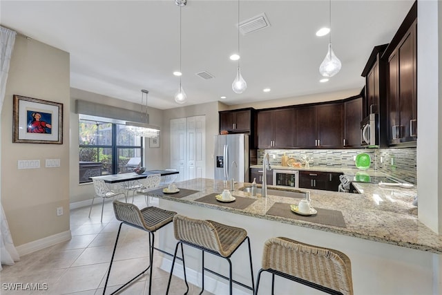 kitchen with sink, hanging light fixtures, kitchen peninsula, stainless steel appliances, and backsplash