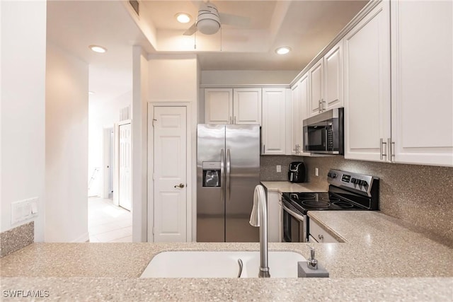 kitchen with decorative backsplash, appliances with stainless steel finishes, light stone countertops, ceiling fan, and white cabinetry