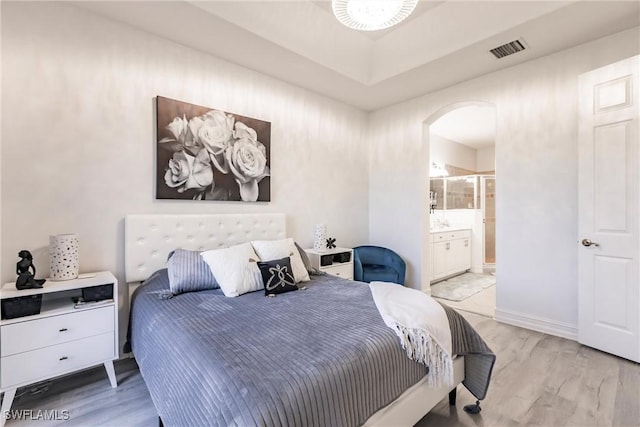 bedroom featuring connected bathroom and light hardwood / wood-style flooring