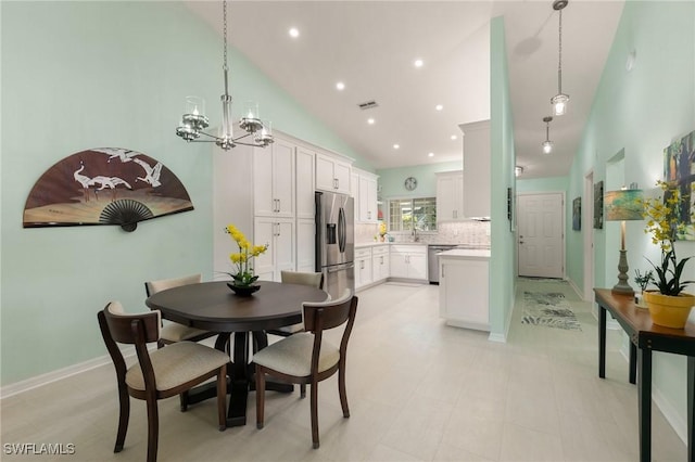 dining space with sink, high vaulted ceiling, and an inviting chandelier