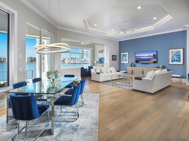 dining area with ceiling fan with notable chandelier, ornamental molding, light hardwood / wood-style floors, and a water view