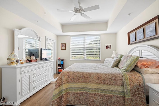 bedroom featuring a raised ceiling, ceiling fan, and hardwood / wood-style flooring