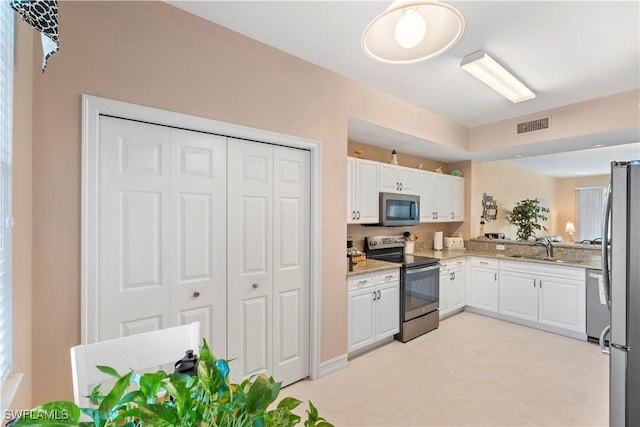 kitchen with light stone counters, sink, white cabinets, and stainless steel appliances