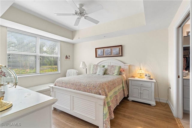 bedroom featuring a tray ceiling, ceiling fan, and light hardwood / wood-style floors