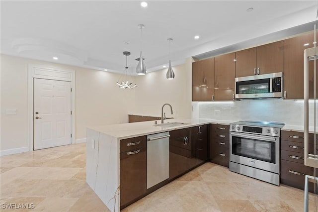 kitchen featuring kitchen peninsula, tasteful backsplash, stainless steel appliances, sink, and pendant lighting