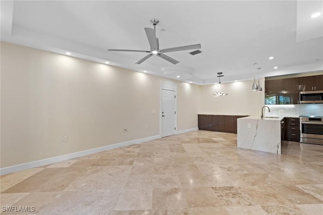 unfurnished living room featuring ceiling fan and sink