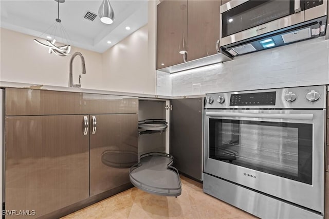 kitchen with pendant lighting, stainless steel appliances, light tile patterned floors, and a raised ceiling