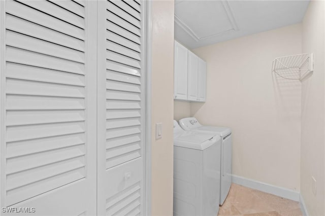 laundry area featuring washer and dryer, light tile patterned floors, and cabinets