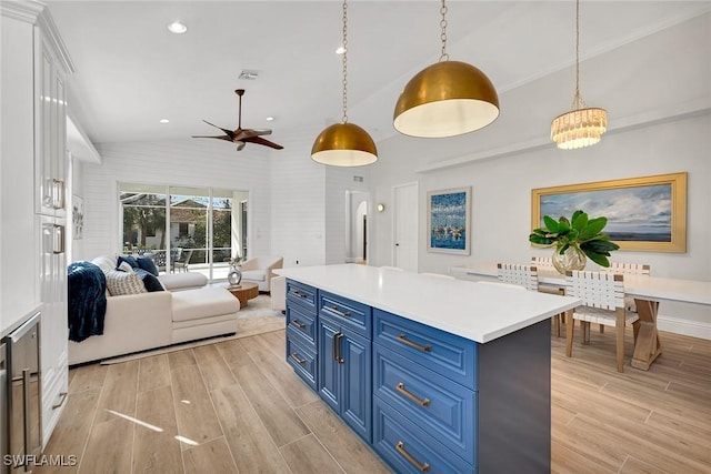 kitchen featuring blue cabinetry, pendant lighting, white cabinets, a center island, and lofted ceiling